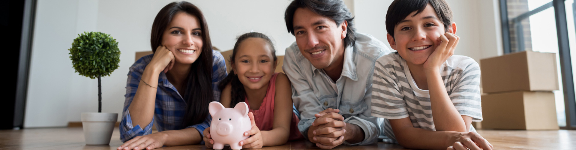 Family laying on the floor holding a piggy bank